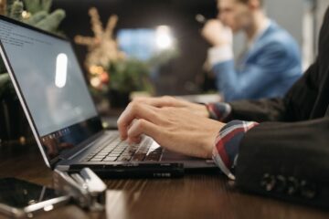 A professional man typing on a laptop in an elegant indoor office setting with a blurred background.