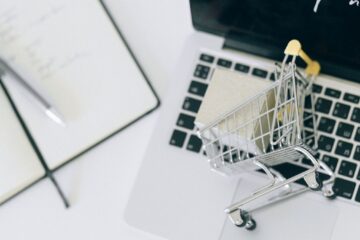 Creative depiction of online shopping with a miniature cart on a laptop keyboard.