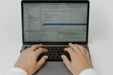 Close-up of hands coding on a laptop, showcasing software development in action.