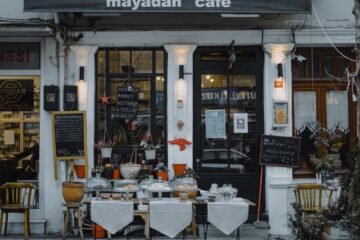 An inviting outdoor café showcasing local food, menu boards, and charming decorations in a quaint neighborhood setting.
