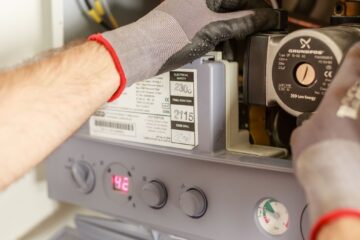 Close-up of hands adjusting a boiler system with precise instrumentation, showing maintenance work.