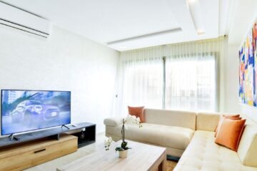 Bright living room featuring modern decor with sofa, TV, and abstract art.